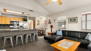 A modern kitchen with a central island, bar stools, a black leather sofa, and a wooden coffee table. - Amazing Sunset View on Canyon Lake! (Canyon Lake)