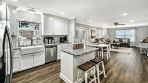 Una cocina moderna con armarios blancos, encimera de granito y una isla central con taburetes de bar.