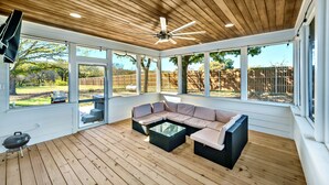 Un porche cubierto con techo de madera, ventanas amplias y un sofá modular.