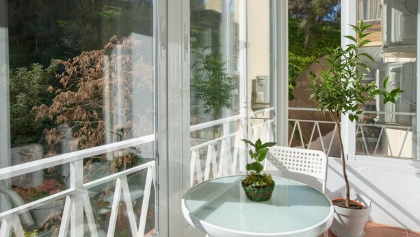 A balcony with a glass table and two potted plants. - Quiet apartment with a nice terrace (Málaga)