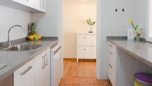 A modern kitchen with white cabinets, a stainless steel sink, and a wooden floor. - Quiet apartment with a nice terrace (Málaga)