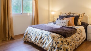 A bedroom with a large bed, a bedside table with a lamp, and a window with curtains. - Quiet apartment with a nice terrace (Málaga)