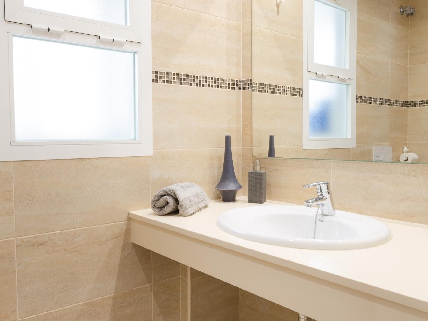 Ein Badezimmer mit einem weißen Waschbecken, einem Spiegel und einem Handtuch auf der Ablagefläche.