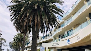 A modern multi-story building with a sign for 'Beachside Accommodation' and 'The Waves'. - STYLISH ISLAND GETAWAY - BEACHFRONT APARTMENT - COWES - Phillip Island (Cowes)