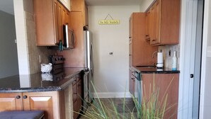 Una cocina compacta con armarios de madera, un refrigerador de acero inoxidable y una encimera con un lavamanos.