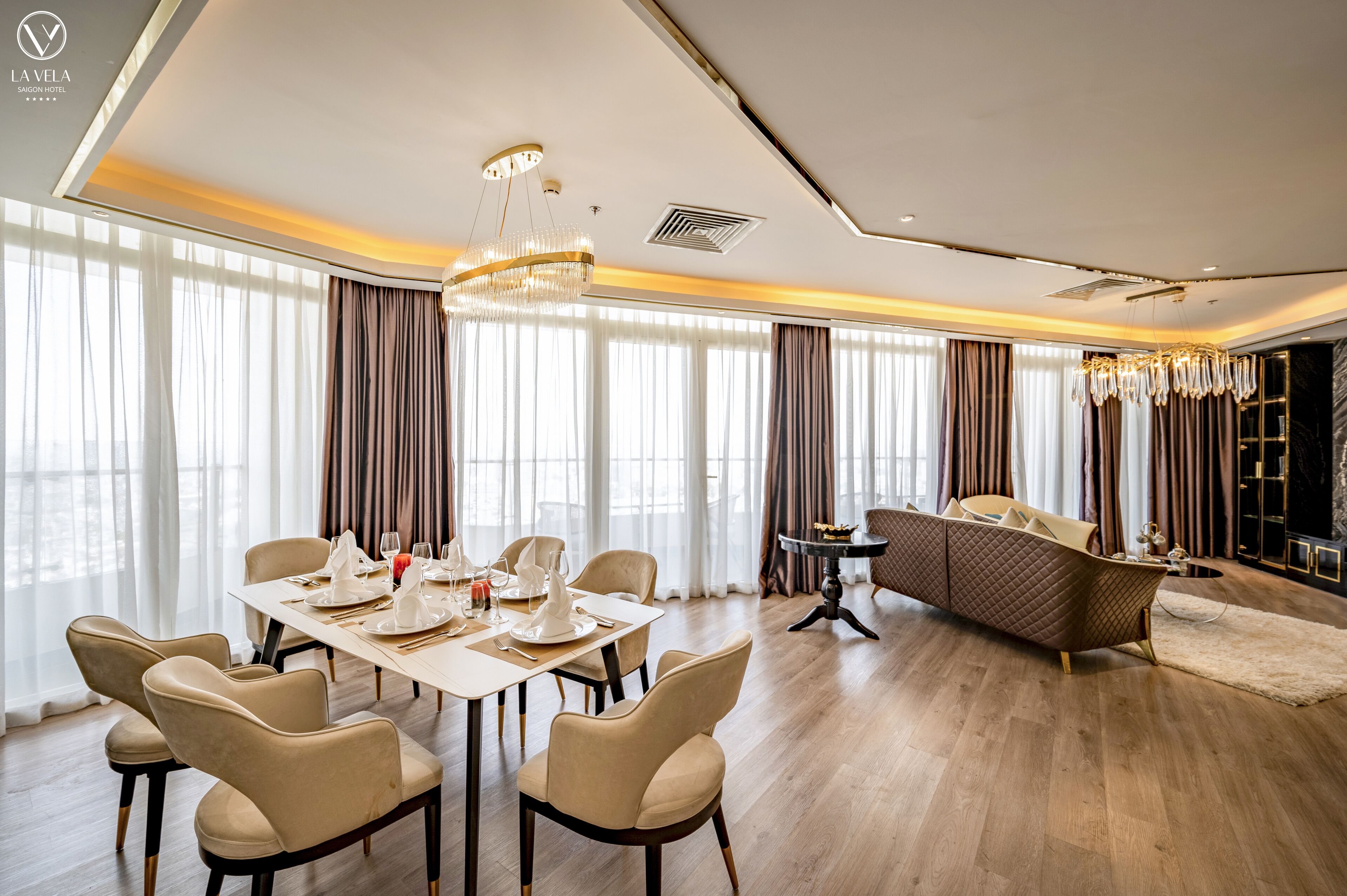 A spacious room with a dining area set for six, a sofa, and a chandelier.