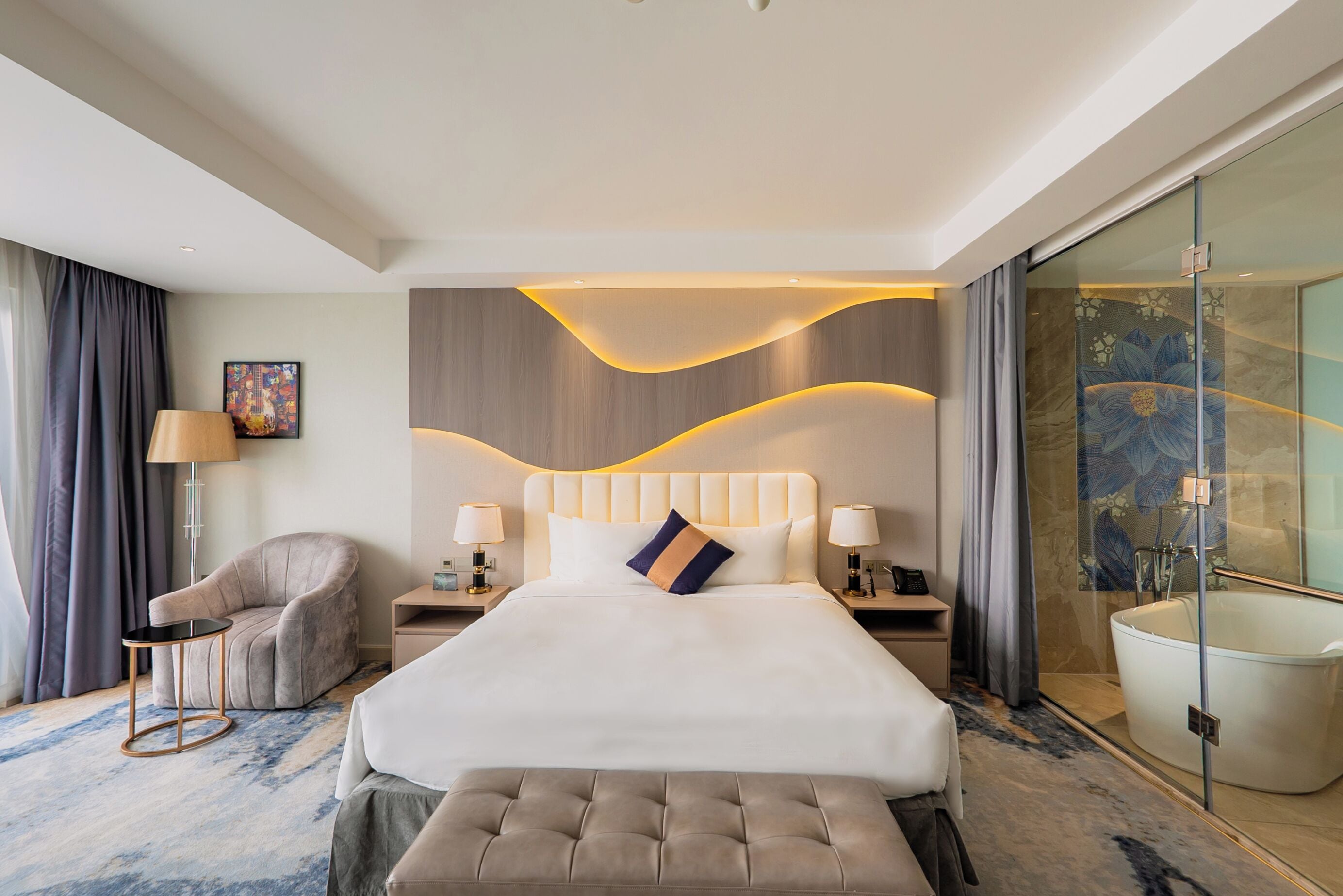 Une chambre d’hôtel moderne dotée d’un grand lit, d’un coin salon, d’une douche en verre et d’un sol en marbre.