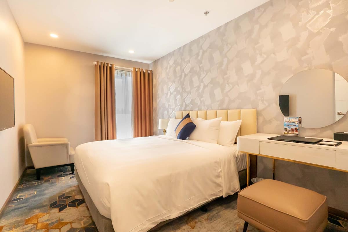 Una habitación de hotel con cama, escritorio, silla y un espejo grande.