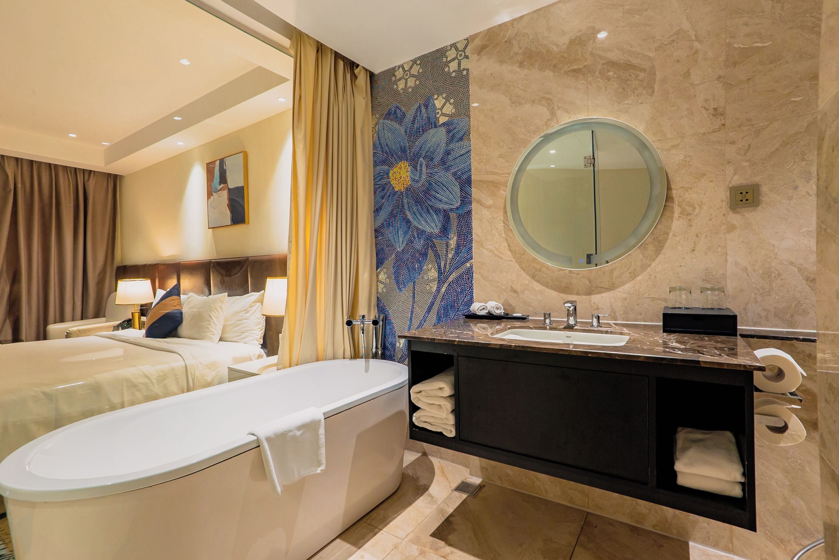 A modern bathroom with a freestanding bathtub, a round mirror, and a marble vanity.
