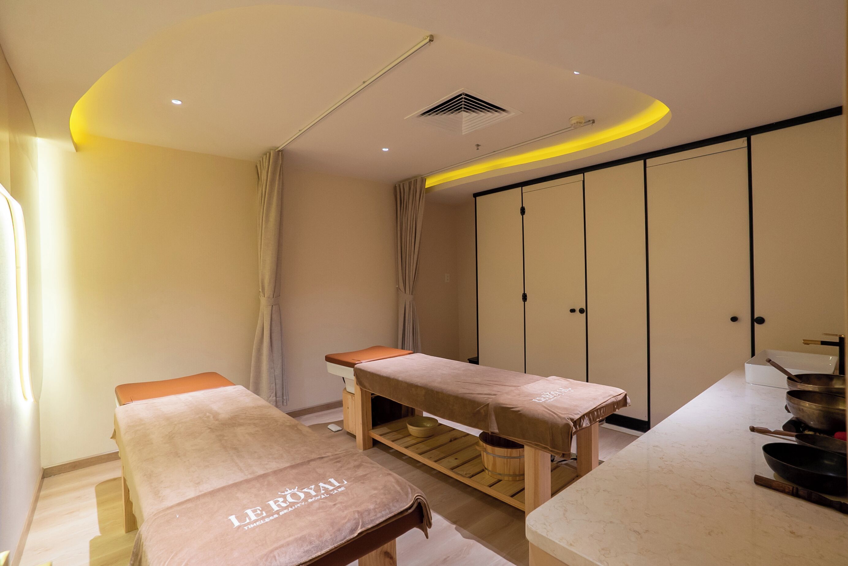A treatment room with two wooden tables, a large cabinet, and a countertop with kitchenware.