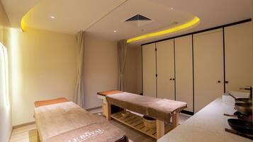 A treatment room with two wooden tables, a large cabinet, and a countertop with kitchenware.