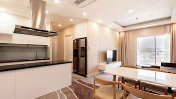 Una cocina moderna con una campana extractora de acero inoxidable, un comedor con una mesa grande y sillas, y vistas de la ciudad a través de un ventanal.