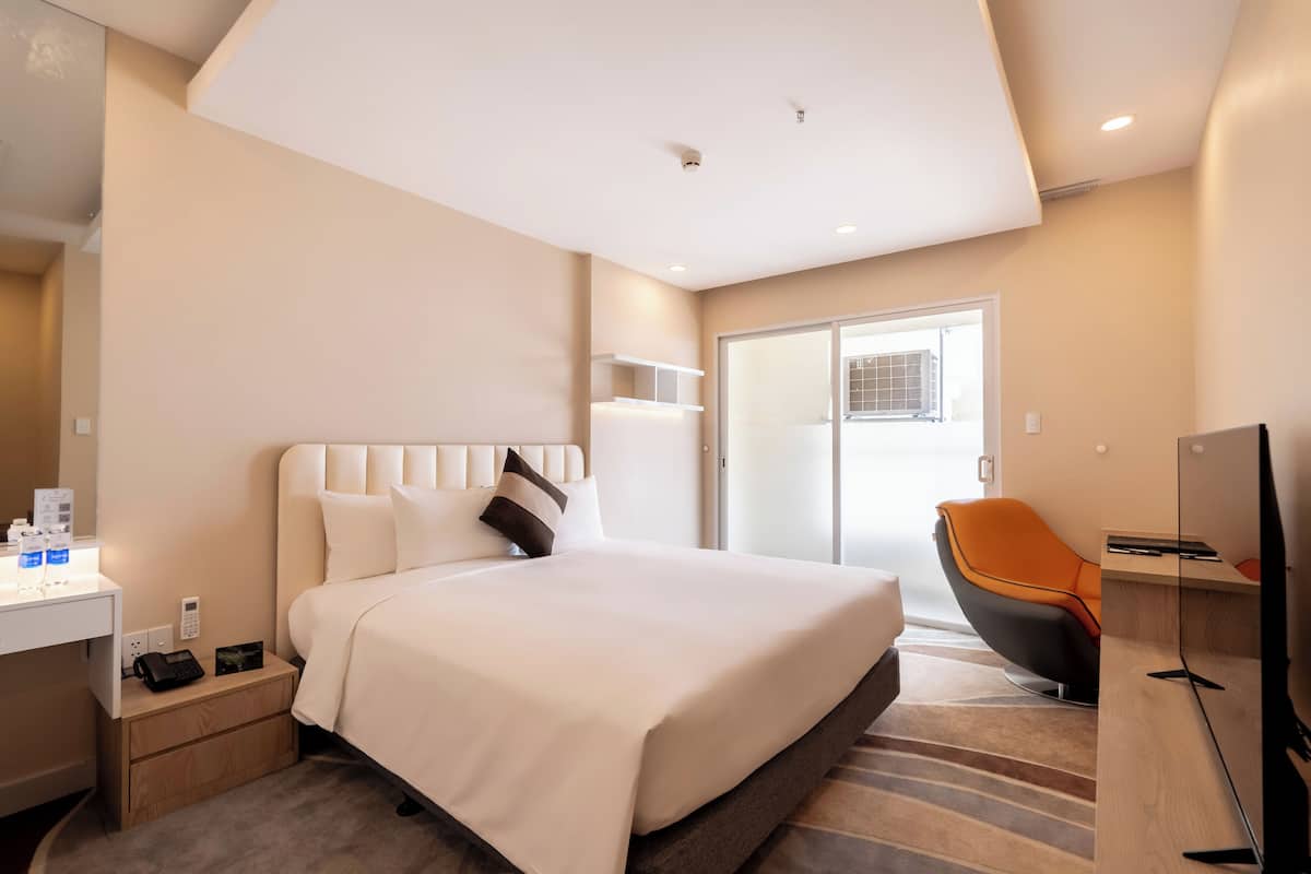 Una habitación de hotel moderna con una cama grande, un escritorio con teléfono, una silla y un televisor.