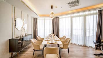 A dining area with a long table set for six, surrounded by six chairs, a console table with a mirror, and a chandelier.