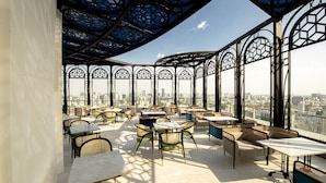 Terraza en la azotea con mobiliario exterior, ventanas amplias y vistas a la ciudad.