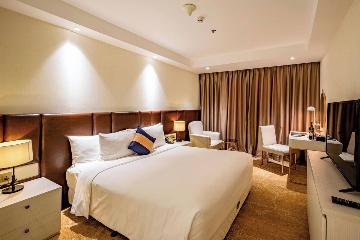 Habitación de hotel con una cama grande, un escritorio con silla, televisor y zona de baño.