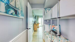 A narrow hallway with bunk beds on one side and a door leading to a room with a bed. - Beachfront, Indoor Pool & Hot Tub (Gulf Shores)