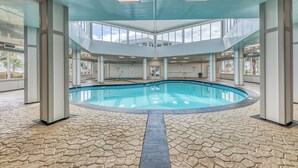 An indoor swimming pool with a hexagonal tile floor, large windows, and a central pool area. - Beachfront, Indoor Pool & Hot Tub (Gulf Shores)