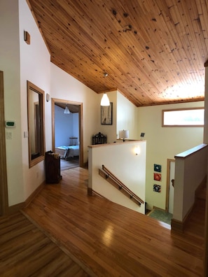 Stylish hallway with a high ceiling, polished wooden planks, and a large window.