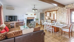 Ein Wohnzimmer mit Kamin, einem Essbereich und einer Küche mit Steinwänden.