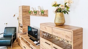 Una sala de estar moderna con televisor, mueble de madera y objetos decorativos.