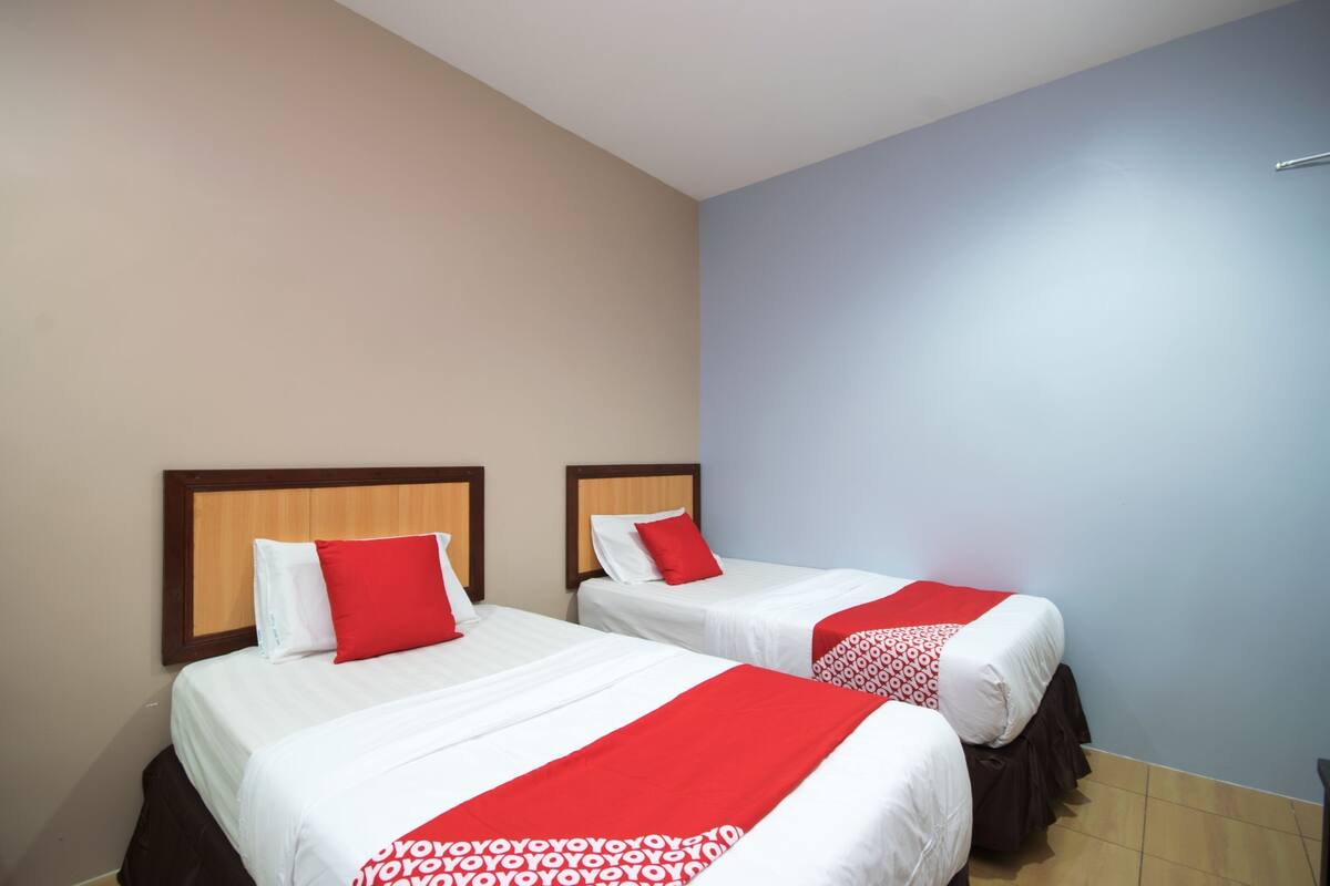 Two single beds with wooden headboards, white bedding, and red accents.