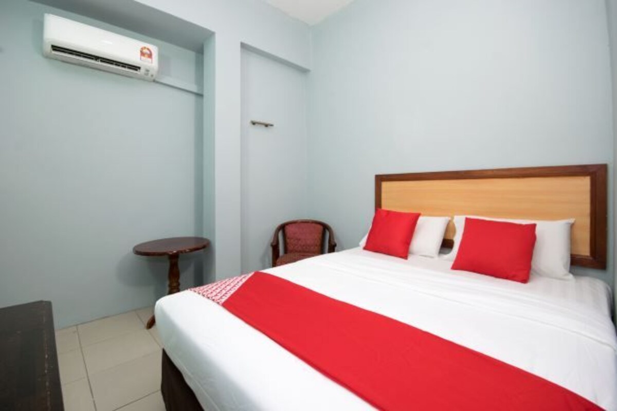 Et hotelværelse med en seng, et rundt bord, en stol og en aircondition.
