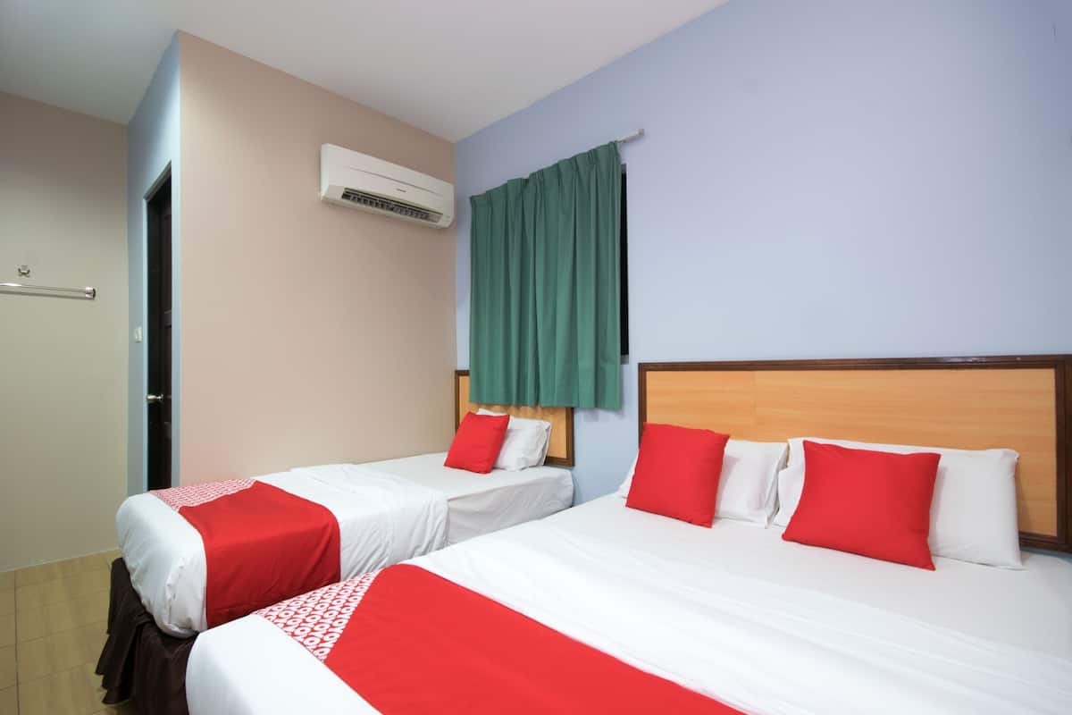 A hotel room with two beds, each with red and white bedding, a wooden headboard, and a green curtain.