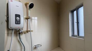 A shower area with a Joven water heater, a handheld showerhead, and a window.