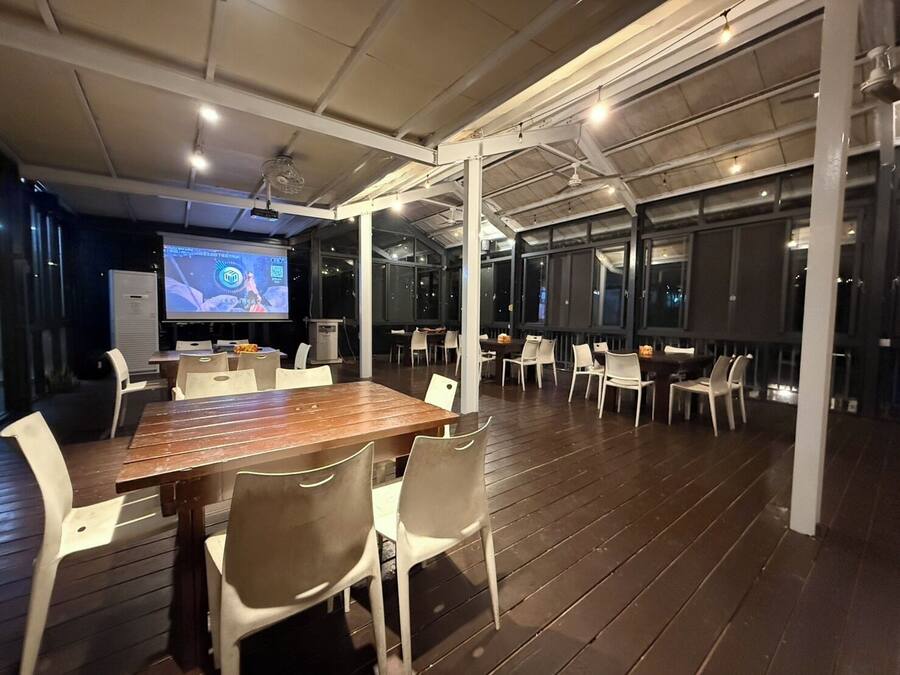 A conference room with a large table, white chairs, and a projection screen.