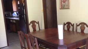 Une table à manger entourée de six chaises en bois, une bougie posée sur la table et un tableau encadré accroché au mur.