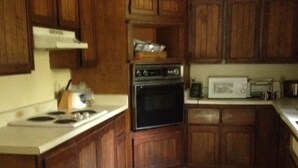 Une cuisine avec des meubles de rangement en bois, une cuisinière, un four, un four à micro-ondes et un grille-pain.
