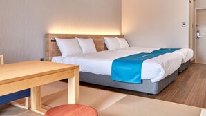 Une chambre d’hôtel avec un lit en bois, une couverture bleue, une table en bois et une chaise rouge.