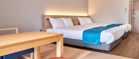 A hotel room with a wooden bed, a blue blanket, a wooden table, and a red chair.