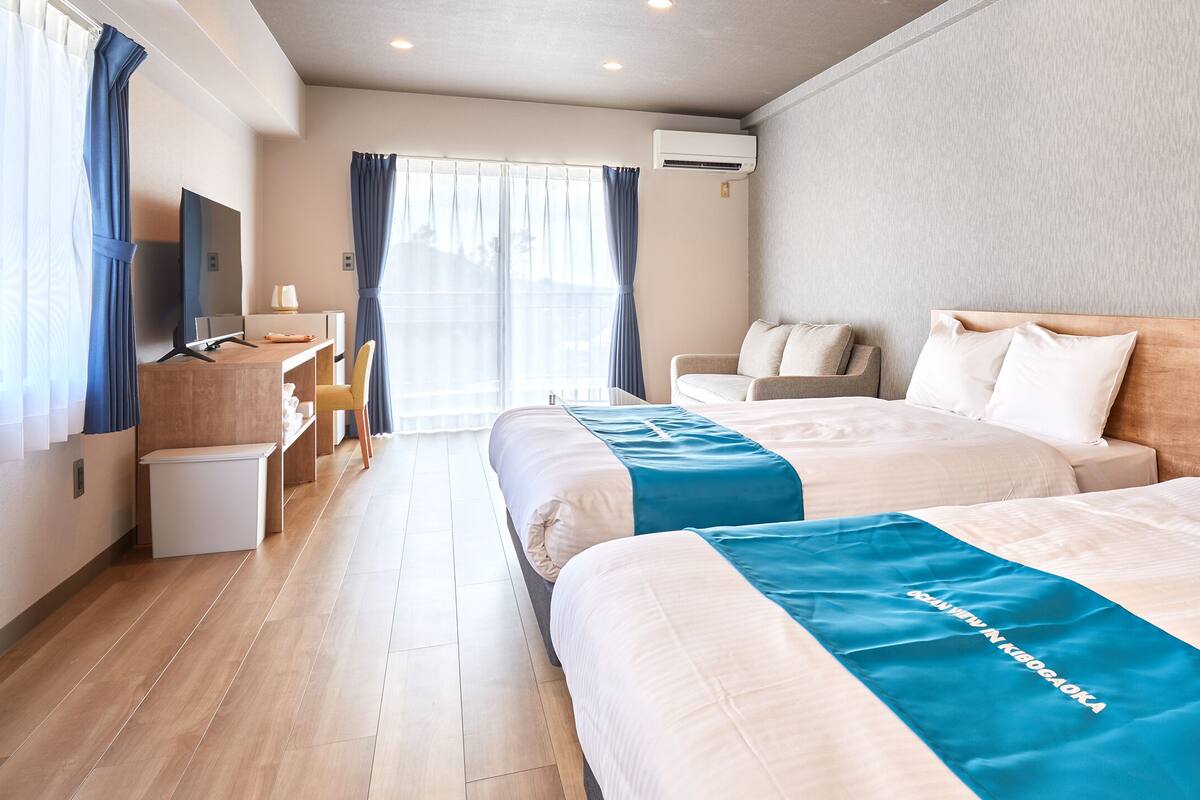 A hotel room with two beds, a TV, a desk, and a chair.
