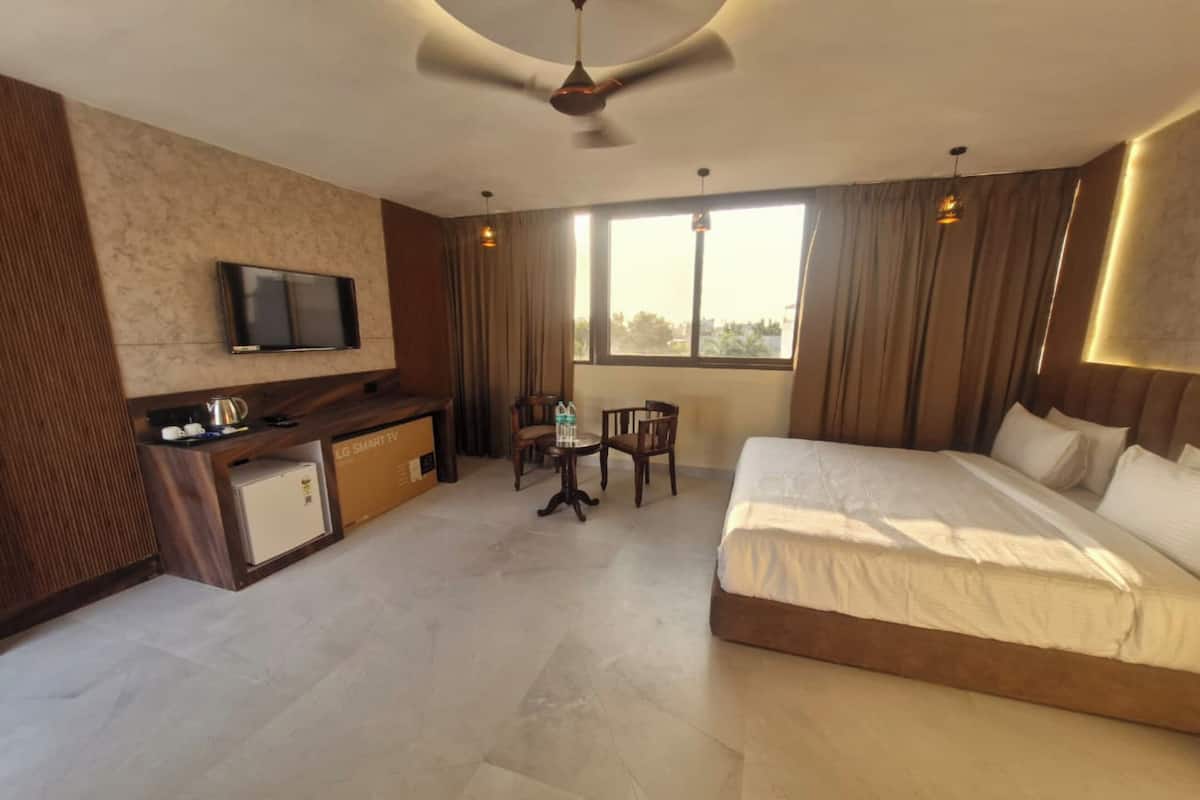 A hotel room with a bed, a desk, a chair, a television, and a window with curtains.