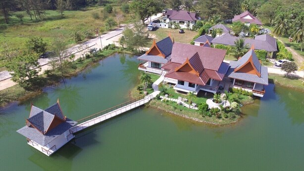 A resort with traditional architecture, a water body, and a bridge connecting the buildings. - Villa Warin Khao Lak (Takua Pa)