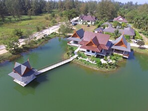 Een resort met traditionele architectuur, een waterpartij en een brug die de gebouwen verbindt.