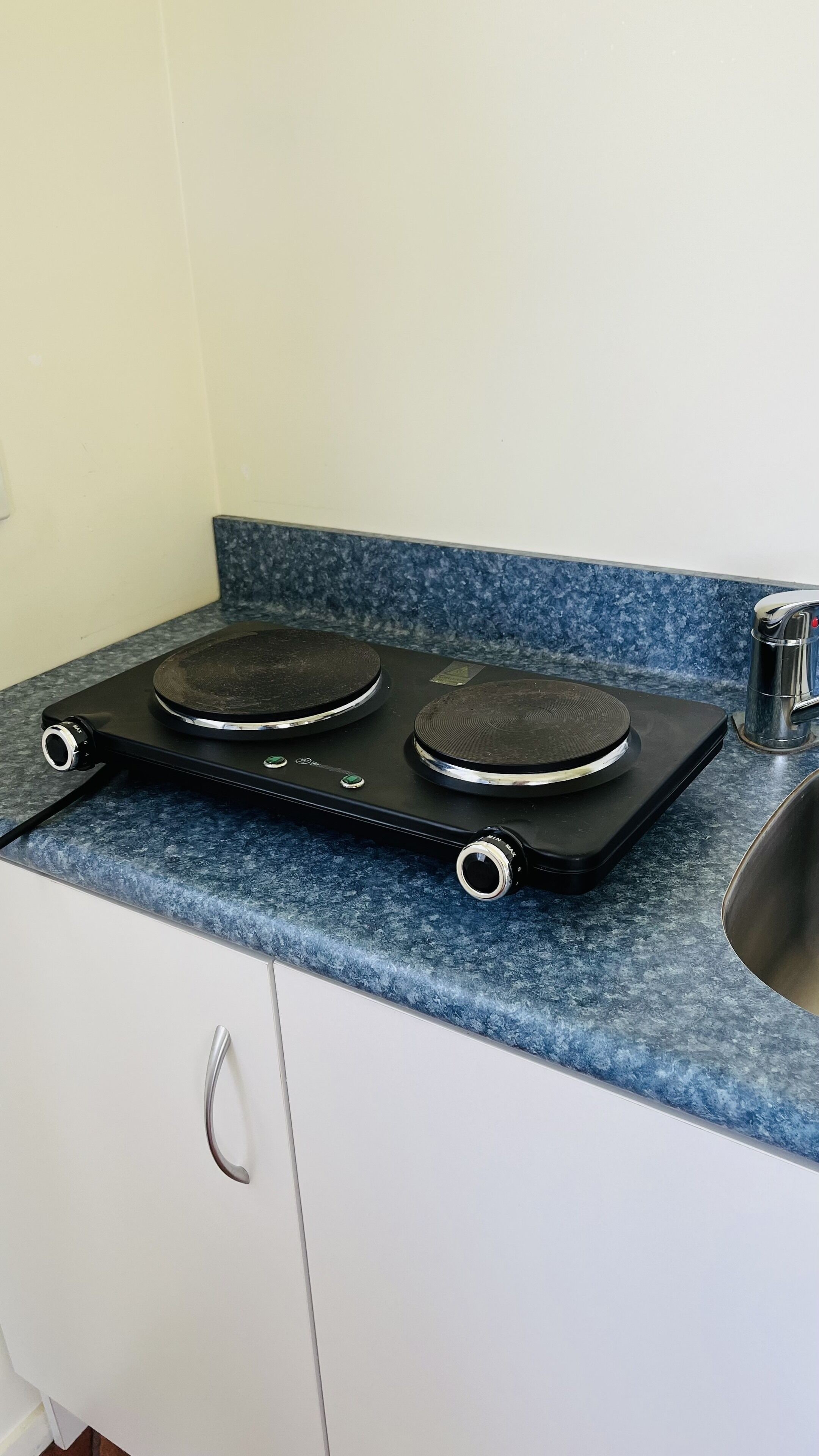 Una cocina con una placa de inducción negra sobre una encimera de granito azul.
