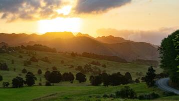 A scenic landscape with rolling hills, a winding road, and a sunset in the background.