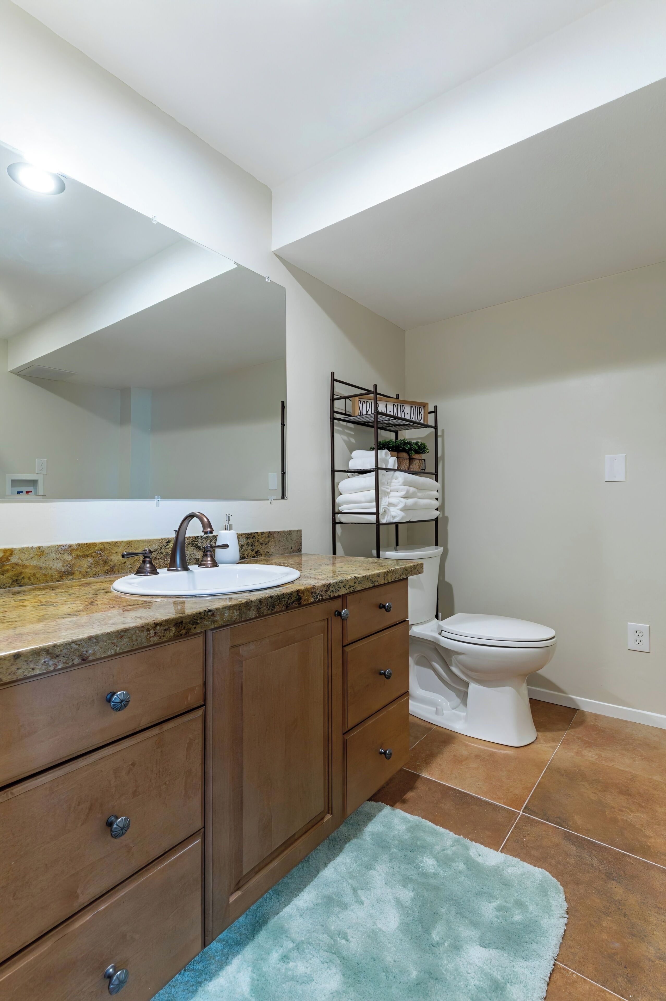 A bathroom with a white sink, a mirror, a towel rack, and a toilet.