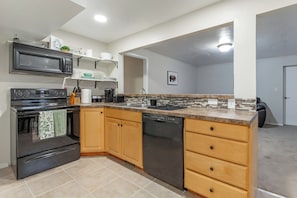 A modern kitchen with a built-in microwave, stove, and dishwasher, wooden cabinets, and a tiled backsplash.