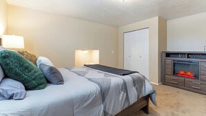 Un dormitorio con cama, lámparas de noche, armario y chimenea.