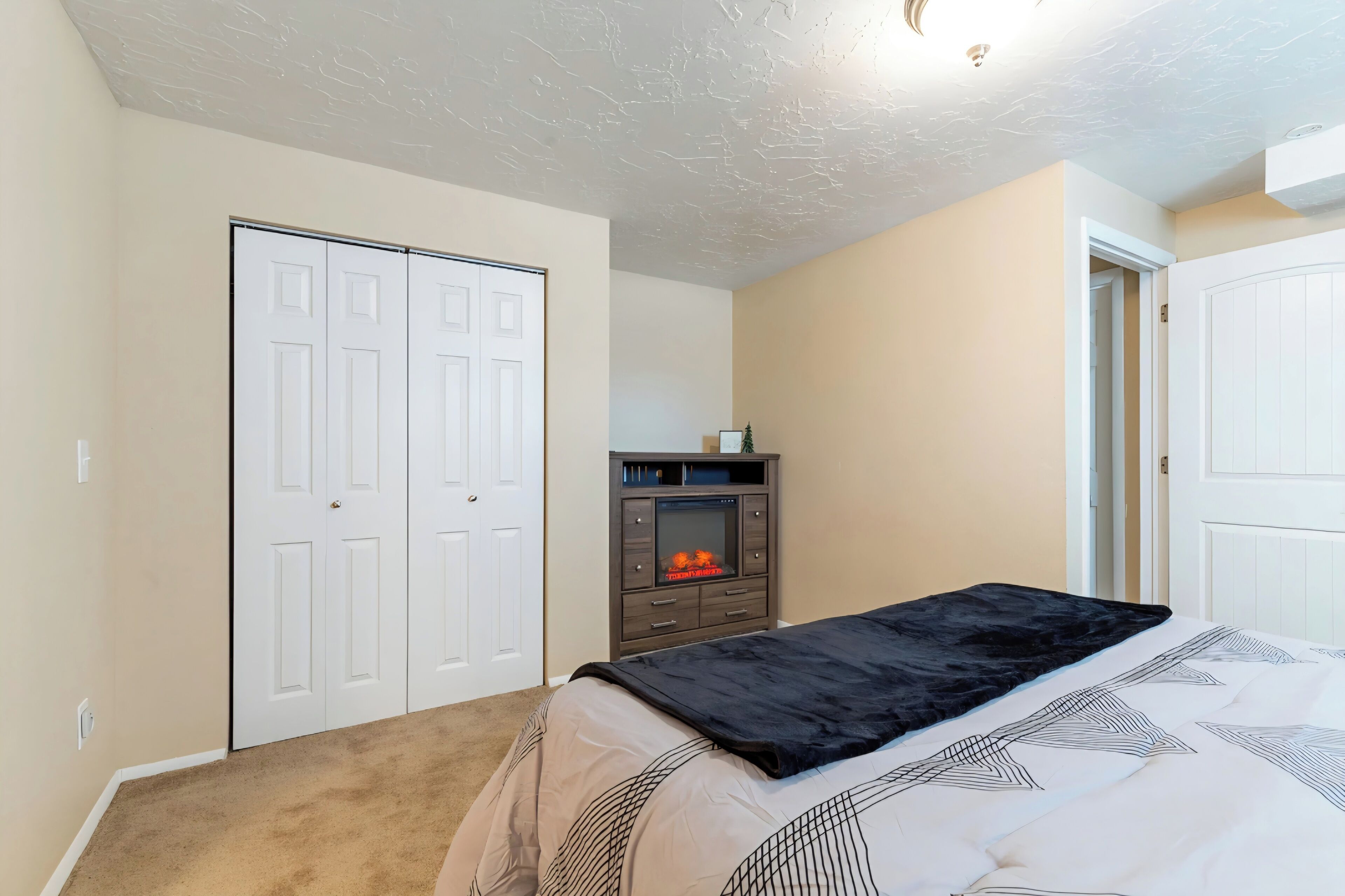 Ein Schlafzimmer mit Bett, Kamin, Schrank und einer Tür.