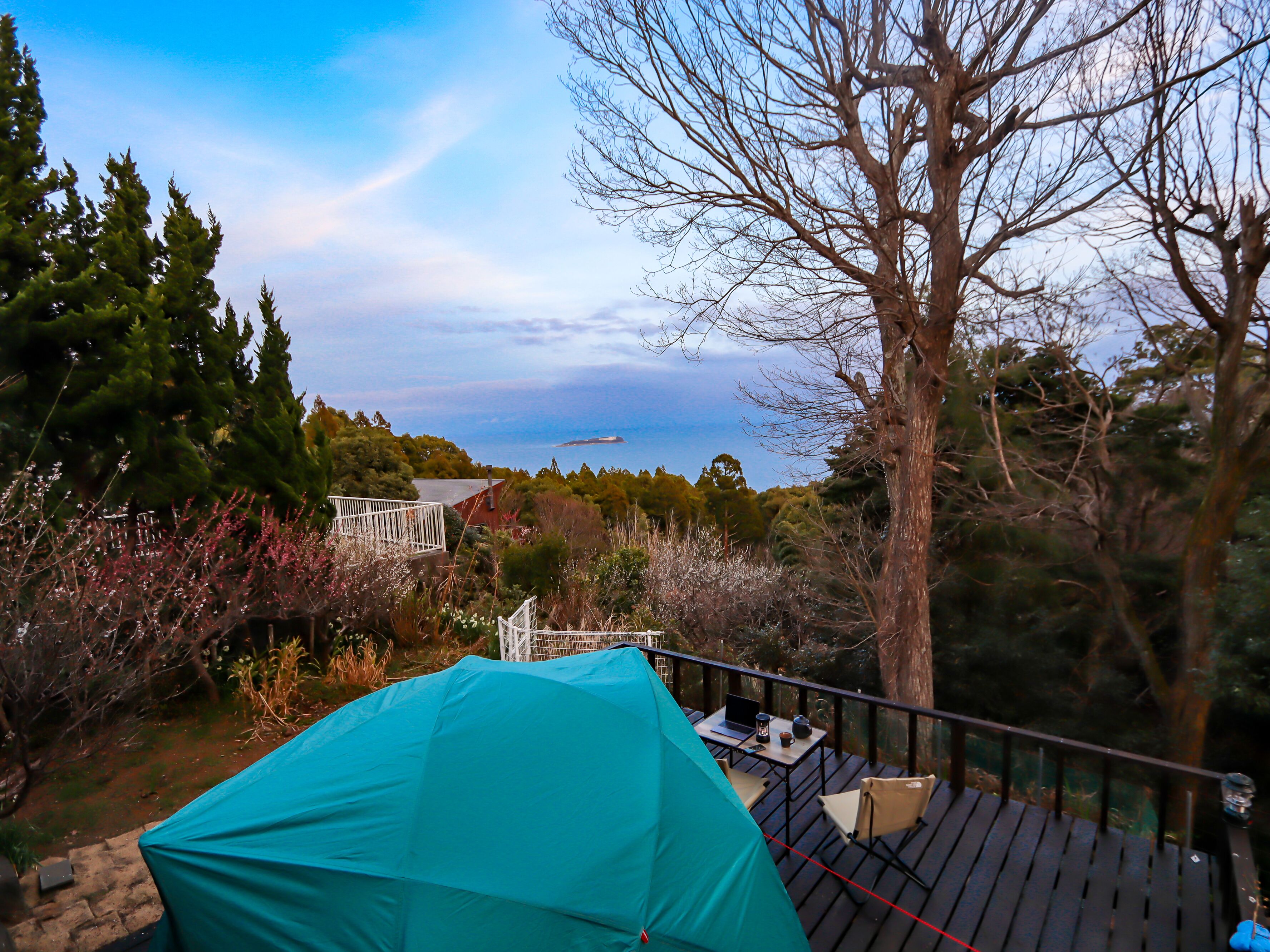 Una terraza con una mesa y sillas, con vista a un cuerpo de agua y una zona boscosa.