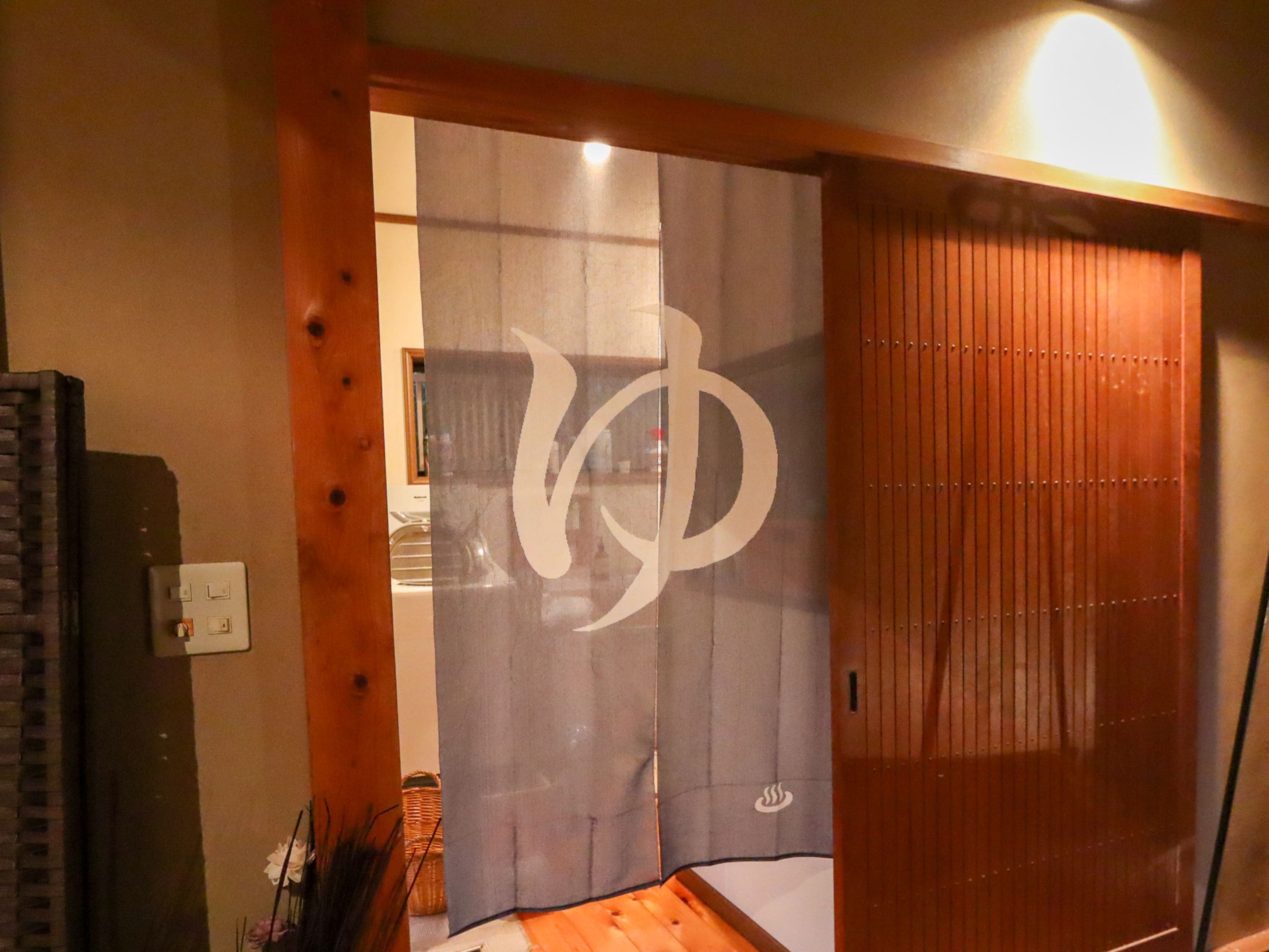 A room with a sliding door featuring a large logo, wooden flooring, and a visible electrical outlet.