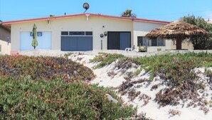 A building with a red roof, a satellite dish, and a thatched roof structure.