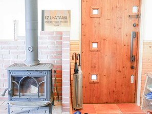 Uma lareira a lenha, uma porta de madeira com puxador e uma placa com a inscrição 'IZU-ATAMI Ocean View House H-41'.