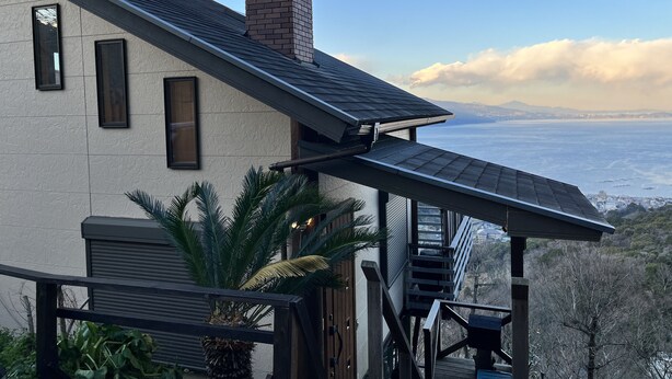 A modern house with a large balcony overlooking a scenic view of the ocean and mountains. - Ocean View House (Atami)