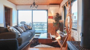 A modern living room with a sofa, coffee table, and a view of the balcony. - Ocean View House (Atami)